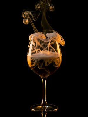 Smoke filling a wine glass, the heavy vapor settling, spilling over the rim in s