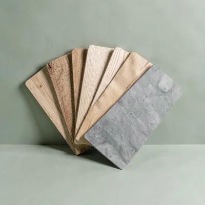 Saturated catalog hero of a fanned set of plank samples on a sage-green color-bl