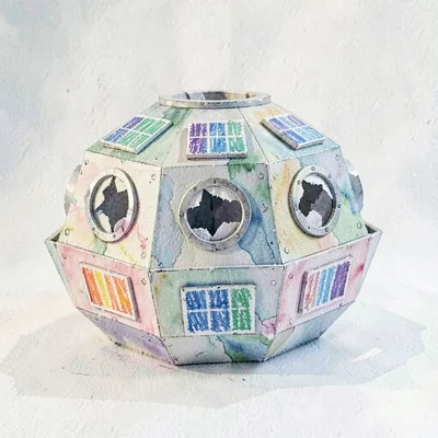 A pop-up paper space-station with torn-paper portholes and crayon-striped solar 