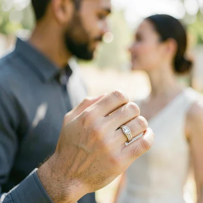 Engagement ring on finger, couple beyond blurred