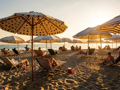 Beach umbrellas casting long golden hour shadows, polka dots meeting stripes, ge
