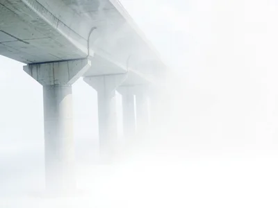 Concrete viaduct fading pier by pier into white emptiness, only the first three