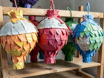 A group of unpainted papier-mâché forms drying on a wooden rack — raw newspaper 