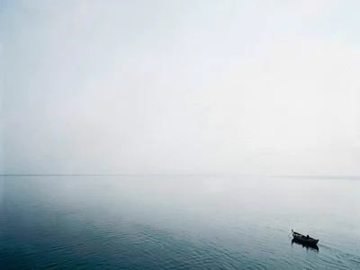 Small boat at frame edge surrounded by endless calm sea