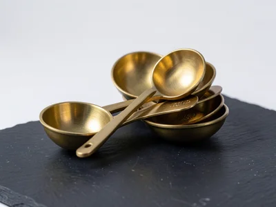 A set of brass measuring spoons nested together, the warm metal catching studio 