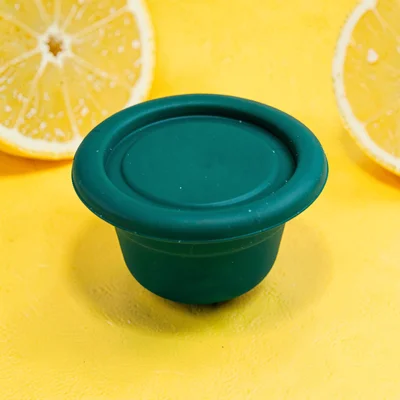 collapsible food-grade silicone container in deep teal flattened top-down on a s