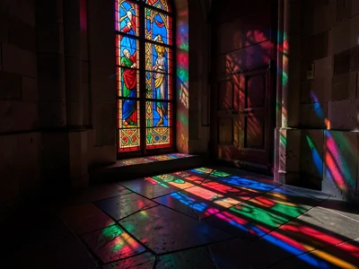 The shadow and light pattern of a stained glass door onto a hallway floor, the g