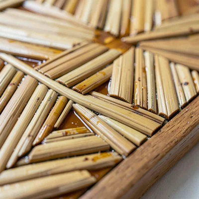 Close-up of the edge of a straw marquetry panel where the lacquered ground meets