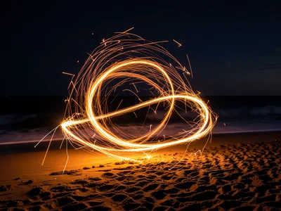 Steel wool spinning long exposure on beach, fire circles and sparks, night ocean