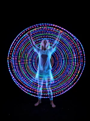 LED hula hoop long exposure, spiral light patterns, dancer's motion as ghost