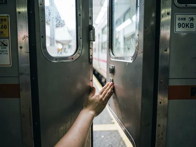 Subway doors caught mid-close, hand preventing the seal, the urban threshold anx