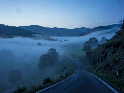 Road curving down into fog with only suggestion of continuation