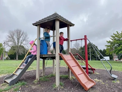 Children on playground equipment under overcast sky, flat light preserving every