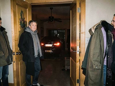 Host watching last guest's taillights disappear, standing in doorway, the relief