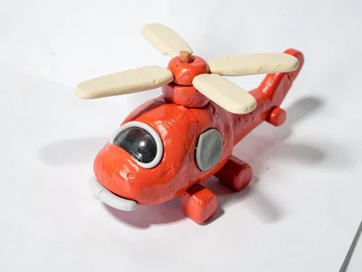 Aerial chunky clay helicopter in cherry red with stubby cream-toned rotor blades
