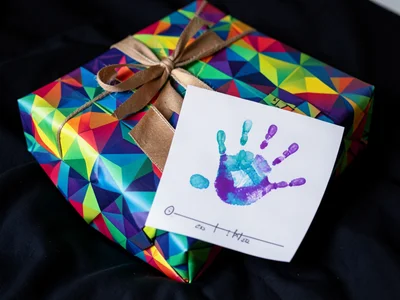 Wrapped gifts on bed with card that shows child's handprint art