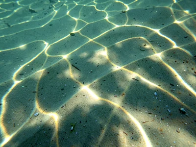 Light focus points creating bright dots across underwater sand