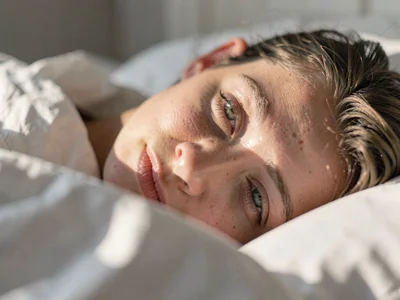 Eyes half-open against morning light, sheets tangled, the blur between dream and