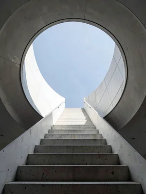 Concrete staircase viewed straight up, steps receding into circle of sky