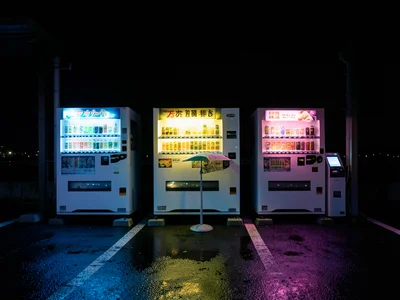 A row of three vending machines at a Japanese highway rest stop at 2am, each a d