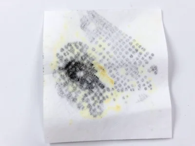 Thermal paper heat damage, dark smear where warm object touched the surface, uni
