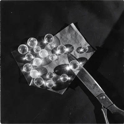 Translucent glass beads and a scissor blade — overlapping transparency depths