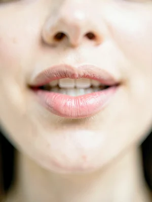 Woman's lower lip caught between her teeth in focus, rest of her face and the pe