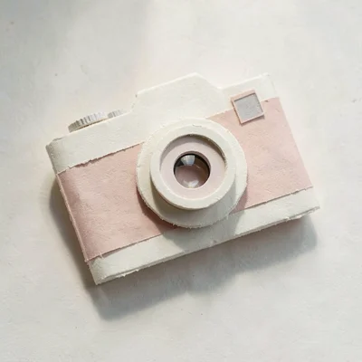 Papercraft onboarding illustration of a layered paper camera with a paper lens r
