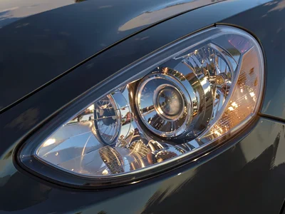 Car headlight detail under painterly lighting setup, chrome and glass as geometr