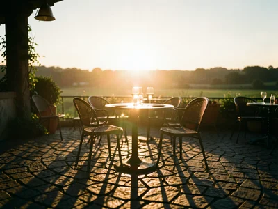 Outdoor cafe terrace bathed in golden light, long shadows on cobblestones, wine 