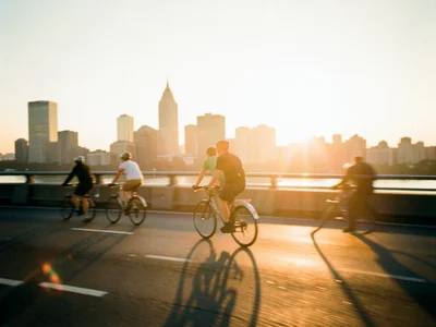 Cyclists crossing a bridge at golden hour, motion blur, city spires behind