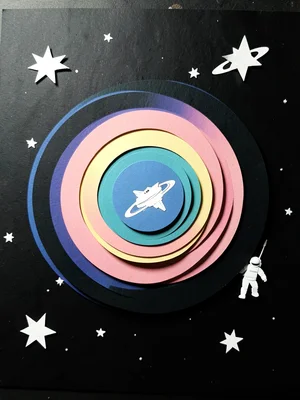 A deep space scene: black background with star cutouts, Saturn rings as concentr