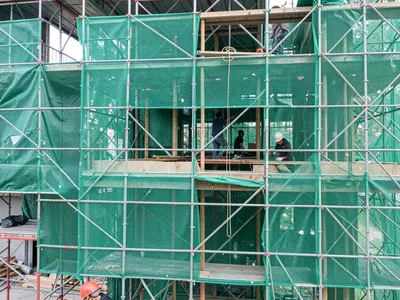 Scaffolding wrapped in green mesh, the chaos of construction contained in grid