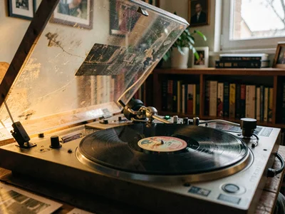 Turntable dust cover being lifted, platter visible, the beginning of a listening