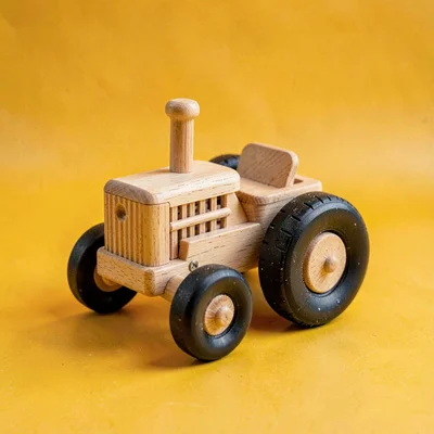 single wooden tractor-shape kid-toy with rubber wheels at slight tilt on a satur
