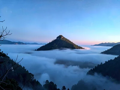 Valley fog below with hilltop island emerging into clear blue