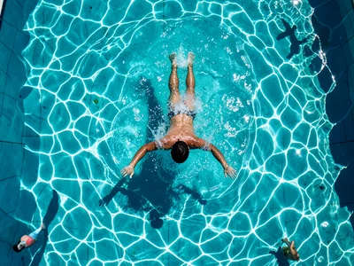 A swimmer emerging from underwater, the moment of breaking the surface, water sh