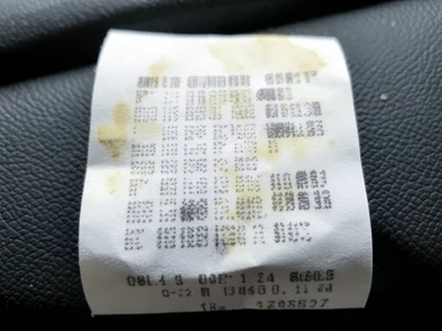 Faded receipt on car dashboard, sun-bleached thermal paper with only the darkest
