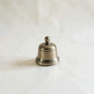 minimal product still of a brass meditation bell on cream paper, soft top light