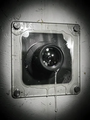 Home security camera mounted on wall, lens reflecting light, 8x10 glass plate we