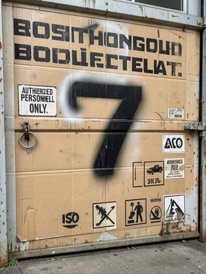 A roll-up steel door on a loading dock, the door number 7 painted in massive dig