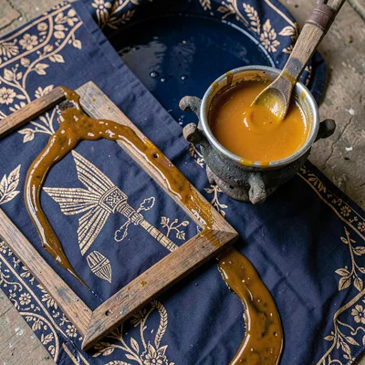 A bowl of molten wax on a small brazier beside a cloth frame, seen from above