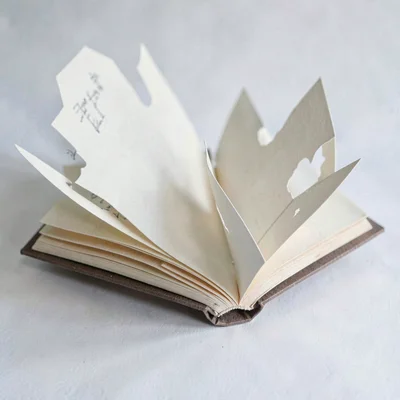 papercraft layered scene of an open paper-cut book with paper-cut pages turning,