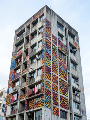 Kente cloth patterns painted on brutalist concrete tower block, geometric color