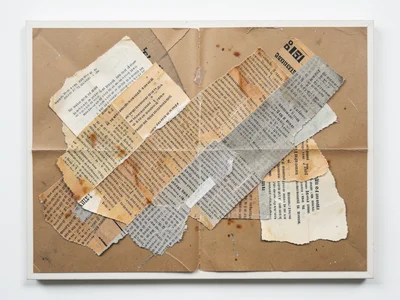 Torn newspaper strips layered diagonally across kraft paper, text fragments visi