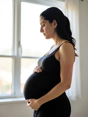 Pregnant woman in profile against bright window, the universal symbol reduced to