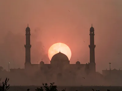 Mosque silhouette against dust-red setting sun
