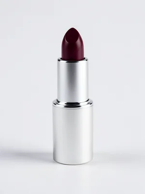 A tube of lipstick, cap off, the bullet twisted up showing a deep berry color, t