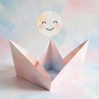 Layered paper composition of a folded paper cradle with a smiling moon above, bl