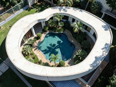 Aerial of a compound: three white curved volumes arranged around a central garde